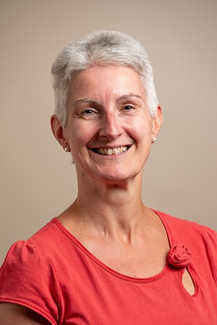 photo of a person with light short hair wearing an orange top
