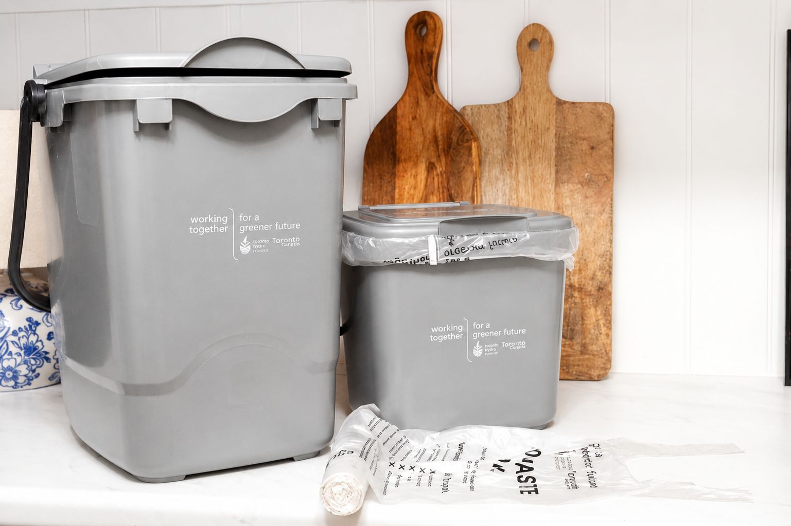 photo of grey small food waste bins next to a wooden chopping board.