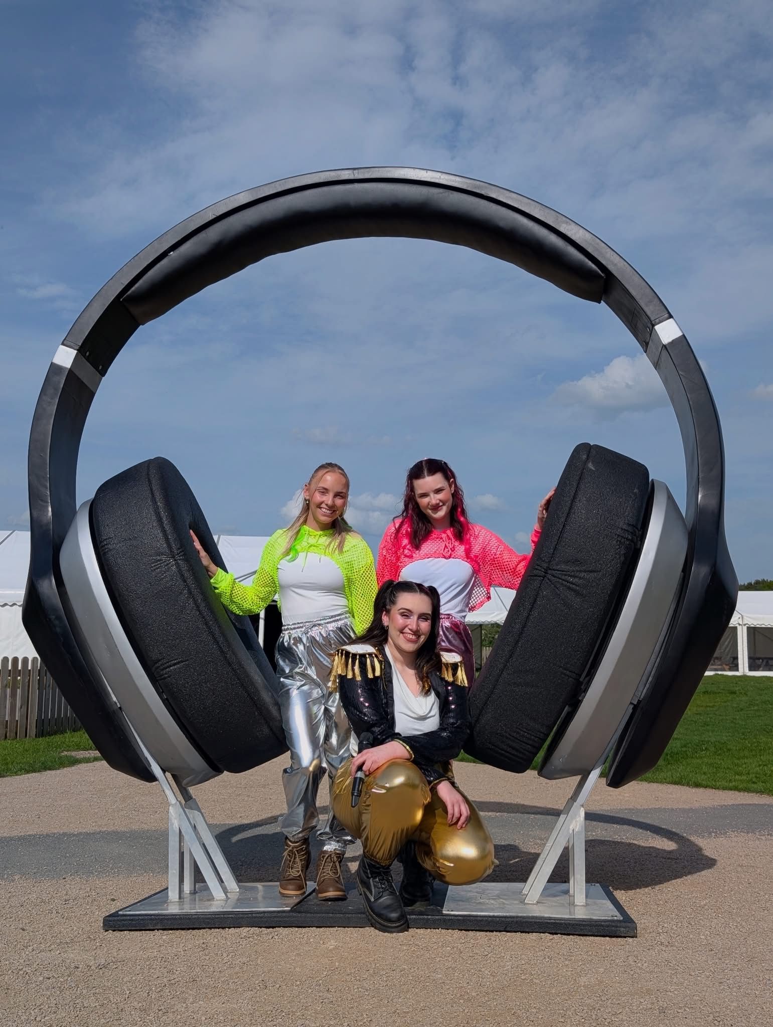 image of large headphones with 3 females wearing a yellow, pink and dark jacket 