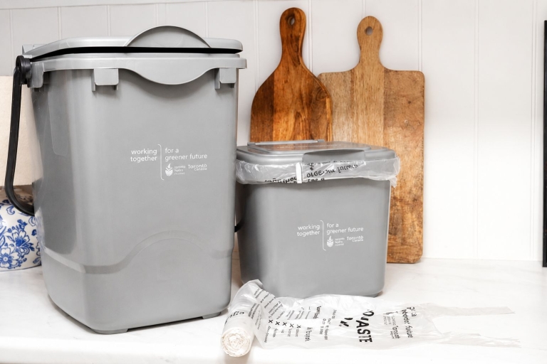 photo of grey small food waste bins next to a wooden chopping board.